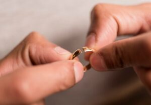 A man is holding his wedding ring in one hand and another on the other.